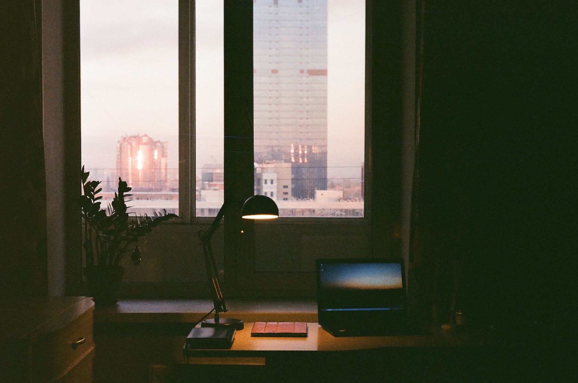 Mesa de trabalho com notebook em escritório com vista para a cidade ao entardecer